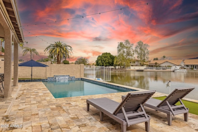 pool at dusk with a patio and a water view