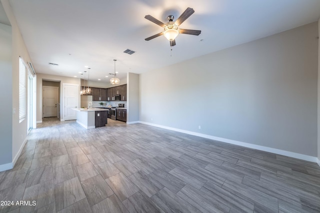 unfurnished living room featuring sink and ceiling fan with notable chandelier