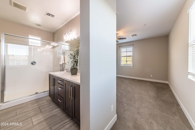 bathroom with vanity, ceiling fan, and a shower with door