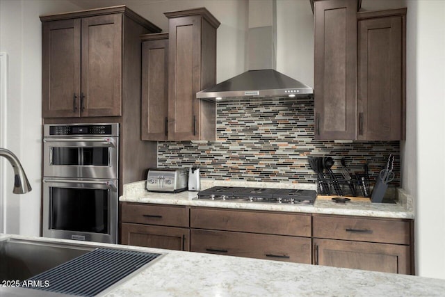 kitchen featuring decorative backsplash, sink, stainless steel appliances, and wall chimney range hood