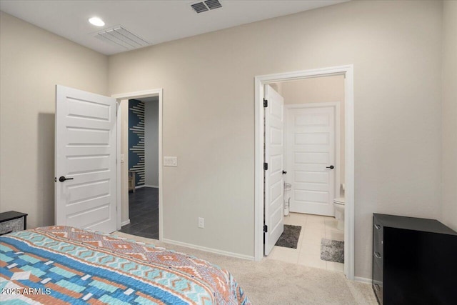 bedroom featuring ensuite bath and light carpet