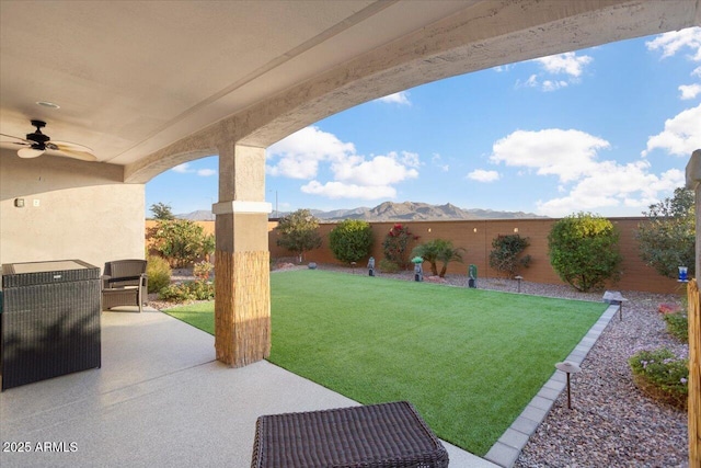 view of yard with a mountain view, ceiling fan, and a patio