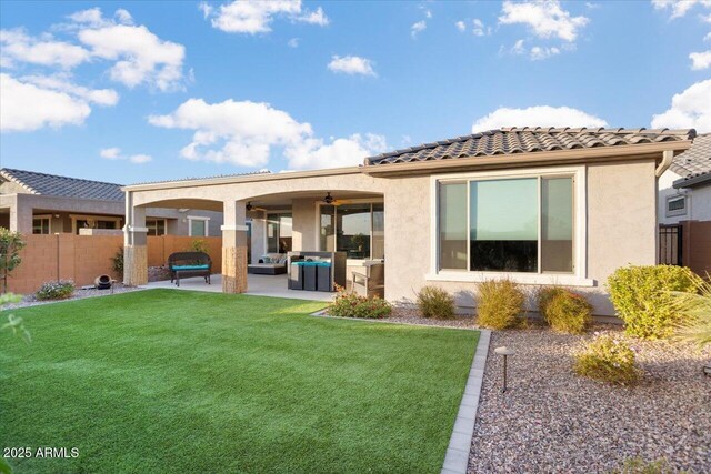 rear view of property featuring outdoor lounge area, ceiling fan, a yard, and a patio