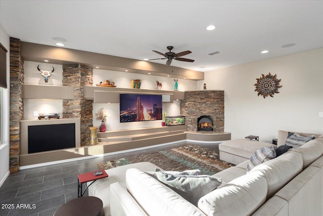 living room featuring a stone fireplace and ceiling fan