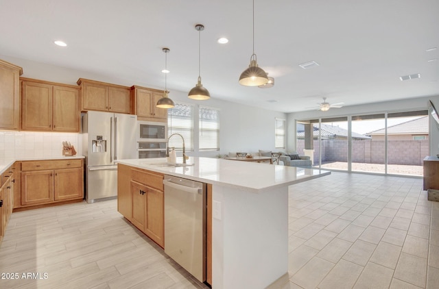 kitchen with a wealth of natural light, appliances with stainless steel finishes, light countertops, and a sink