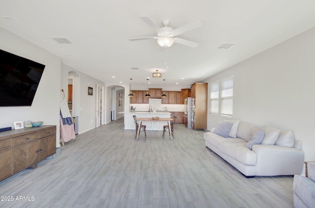 living room featuring arched walkways, visible vents, and light wood-style flooring