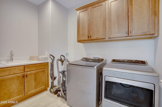laundry room featuring light wood-style flooring, a sink, washing machine and clothes dryer, and cabinet space