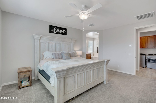 bedroom with visible vents, washer and dryer, light carpet, and arched walkways
