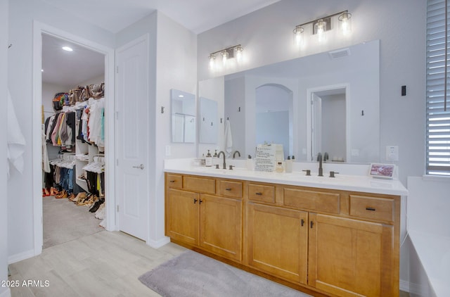 full bath featuring a walk in closet, visible vents, double vanity, and a sink