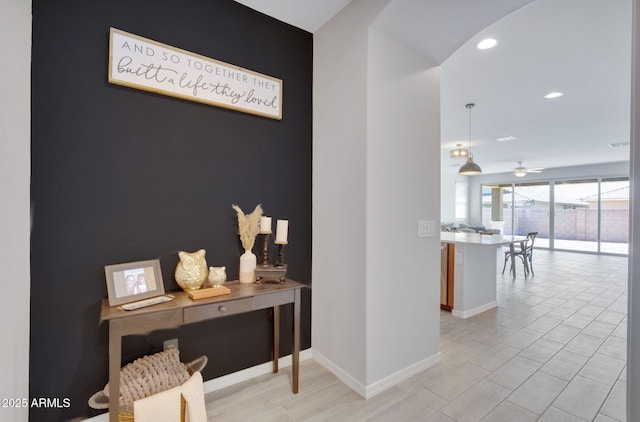 hall with recessed lighting, arched walkways, and baseboards