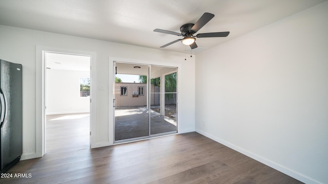 empty room with dark wood-style flooring, a ceiling fan, and baseboards