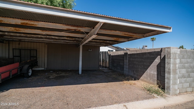 view of parking with fence and a carport