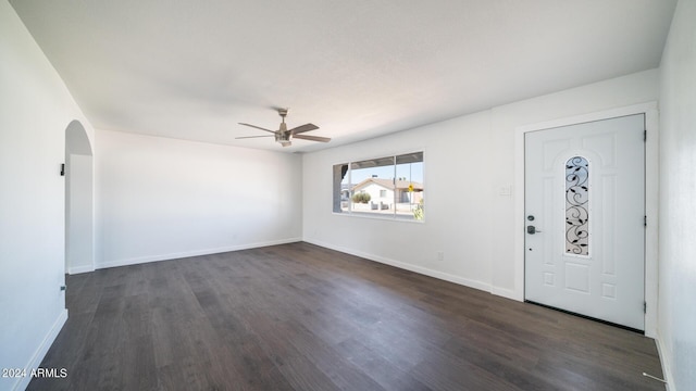 entryway featuring arched walkways, ceiling fan, dark wood finished floors, and baseboards