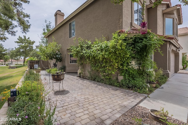 533 N Cobblestone St, Gilbert, AZ 85234 - view of home's exterior featuring stucco siding, a tiled roof, a patio, a garage, and a chimney