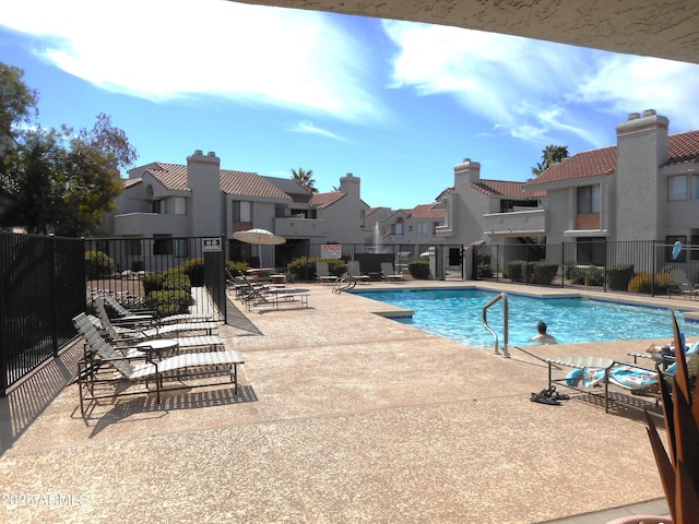 community pool with a residential view, a patio area, and fence