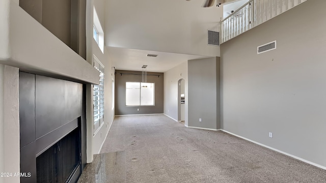 carpeted entrance foyer featuring ceiling fan and a towering ceiling