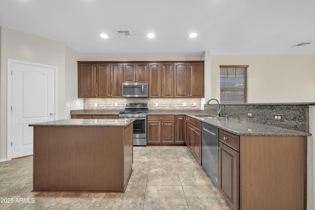 17429 W Red Bird Rd, Surprise, AZ 85387 - kitchen featuring decorative backsplash, a sink, a peninsula, dark stone counters, and stainless steel appliances