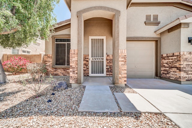 17429 W Red Bird Rd, Surprise, AZ 85387 - property entrance with a garage, driveway, stone siding, and stucco siding