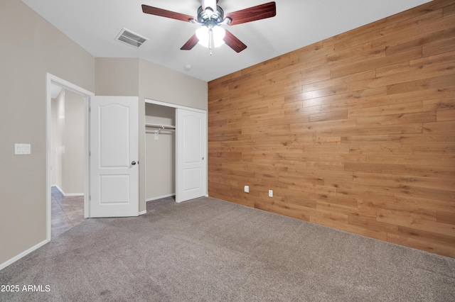 17429 W Red Bird Rd, Surprise, AZ 85387 - unfurnished bedroom with visible vents, a ceiling fan, a closet, wooden walls, and carpet flooring