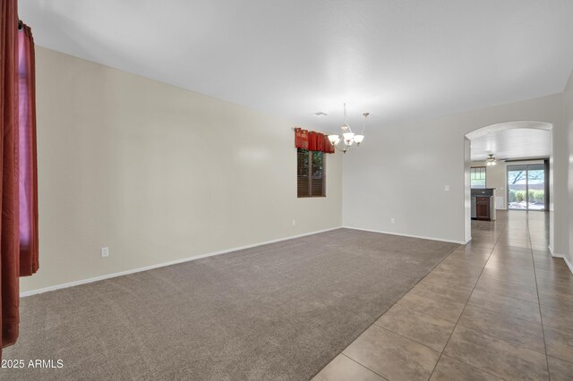 17429 W Red Bird Rd, Surprise, AZ 85387 - tiled spare room featuring arched walkways, baseboards, carpet, and ceiling fan with notable chandelier