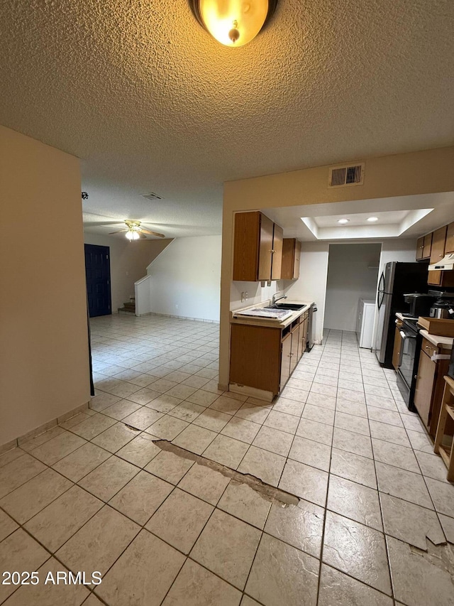 4231 N 69th Dr Unit 1297, Phoenix, AZ 85033 - kitchen with black electric range oven, light countertops, open floor plan, a textured ceiling, and brown cabinetry