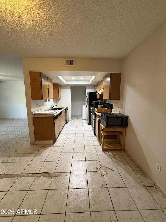 4231 N 69th Dr Unit 1297, Phoenix, AZ 85033 - kitchen with a textured ceiling, black appliances, light countertops, brown cabinets, and light tile patterned floors