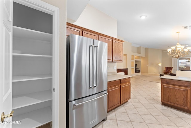 kitchen featuring a chandelier, high quality fridge, light tile patterned flooring, light countertops, and brown cabinets