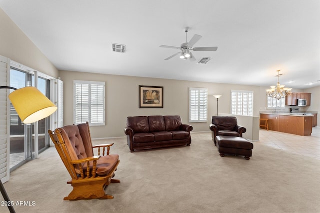 living area featuring light colored carpet, vaulted ceiling, visible vents, and ceiling fan with notable chandelier