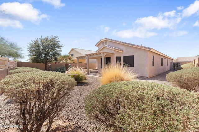 exterior space featuring a pergola, fence, and stucco siding