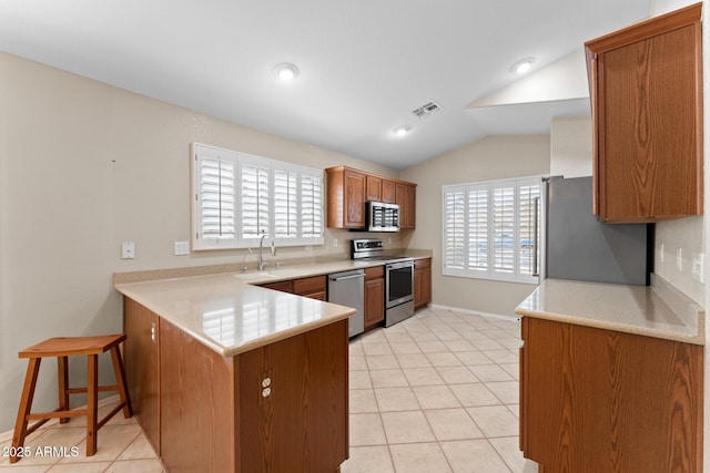 kitchen with visible vents, lofted ceiling, a peninsula, stainless steel appliances, and a sink