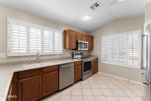 kitchen with visible vents, appliances with stainless steel finishes, vaulted ceiling, light countertops, and a sink