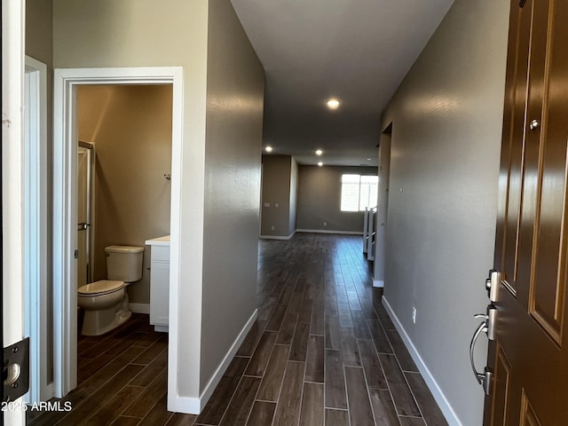 hallway featuring wood finish floors, baseboards, and recessed lighting