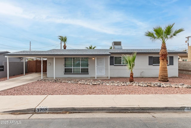 single story home featuring a carport, driveway, and fence