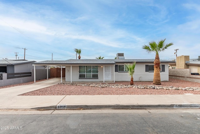 ranch-style house featuring a carport, driveway, a shingled roof, and fence