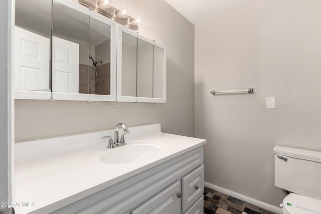 full bath featuring stone finish flooring, baseboards, toilet, and vanity