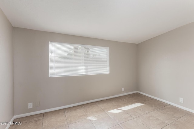 unfurnished room with light tile patterned floors and baseboards