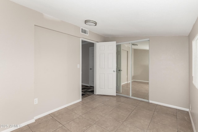 unfurnished bedroom featuring visible vents, baseboards, a closet, and light tile patterned flooring