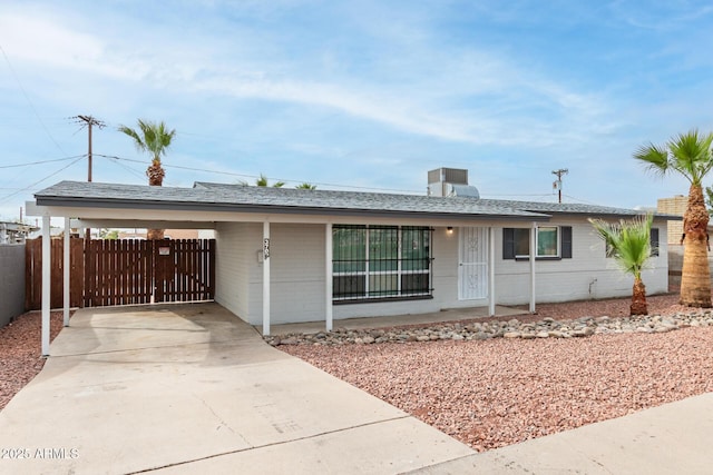 single story home with concrete driveway, fence, roof with shingles, and a carport