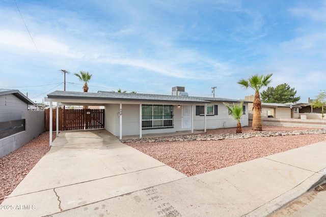 ranch-style home featuring concrete driveway, fence, and a carport