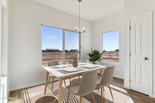 dining space with a notable chandelier, baseboards, and wood finished floors