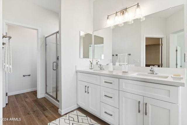 bathroom with wood-type flooring, a shower with door, and vanity