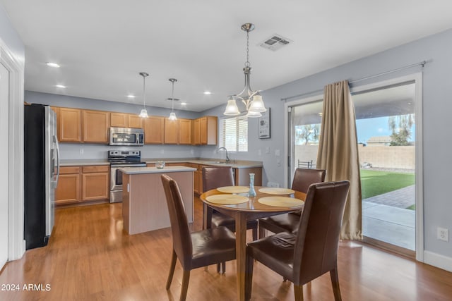 dining space featuring a notable chandelier, sink, and light hardwood / wood-style flooring