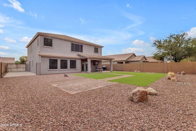 rear view of house featuring a lawn and a patio