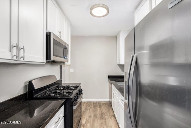 kitchen featuring dark stone countertops, white cabinets, and appliances with stainless steel finishes