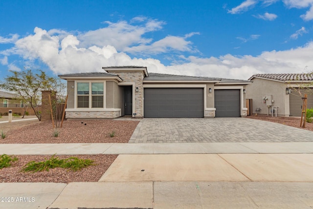 prairie-style house featuring stucco siding, decorative driveway, fence, a garage, and a tiled roof