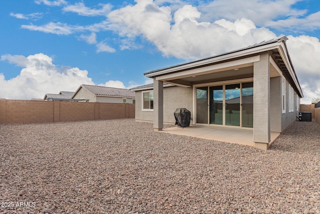 back of house featuring a fenced backyard, a patio area, central AC, and stucco siding