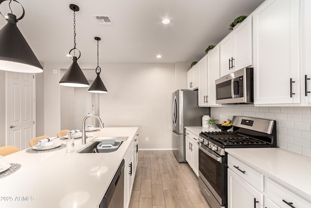 kitchen with visible vents, light countertops, decorative backsplash, appliances with stainless steel finishes, and a sink