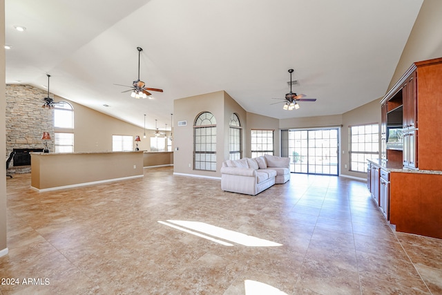 unfurnished living room with a stone fireplace, high vaulted ceiling, and ceiling fan