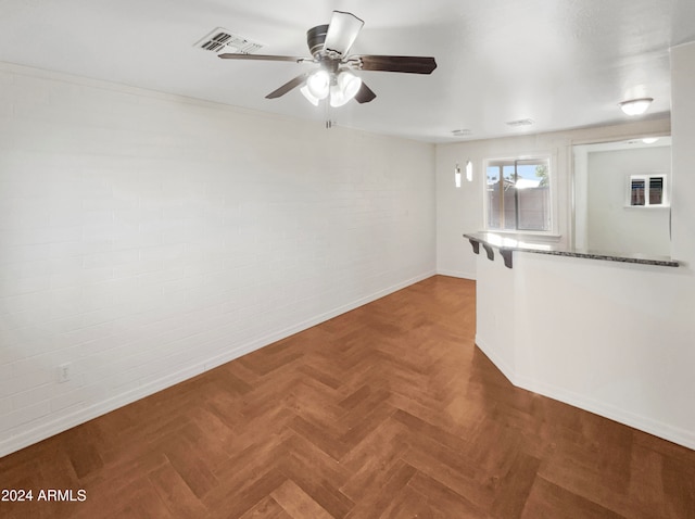 spare room with ceiling fan, brick wall, and parquet floors