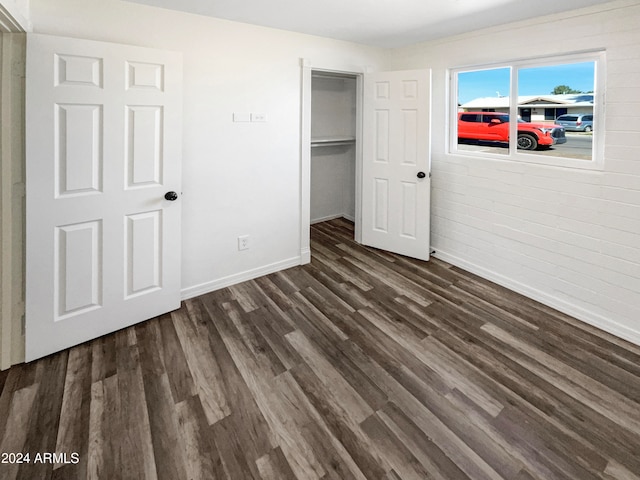 unfurnished bedroom with a closet, dark wood-type flooring, and a spacious closet